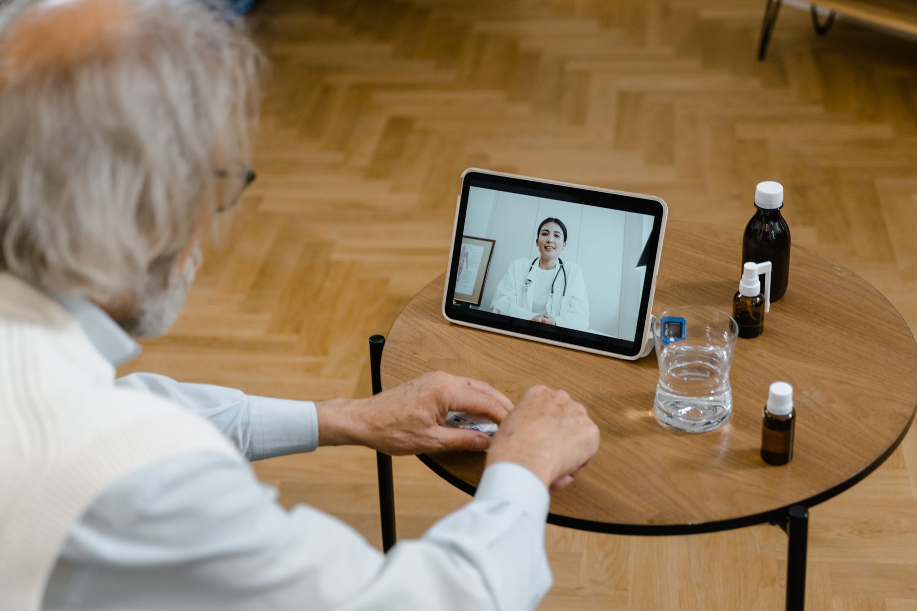 An elderly man participates in a telemedicine session using a tablet.