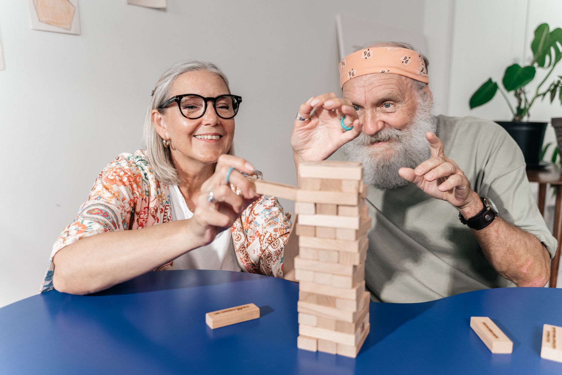 Senior couple enjoying a game of Jenga indoors, sharing laughter and fun.
