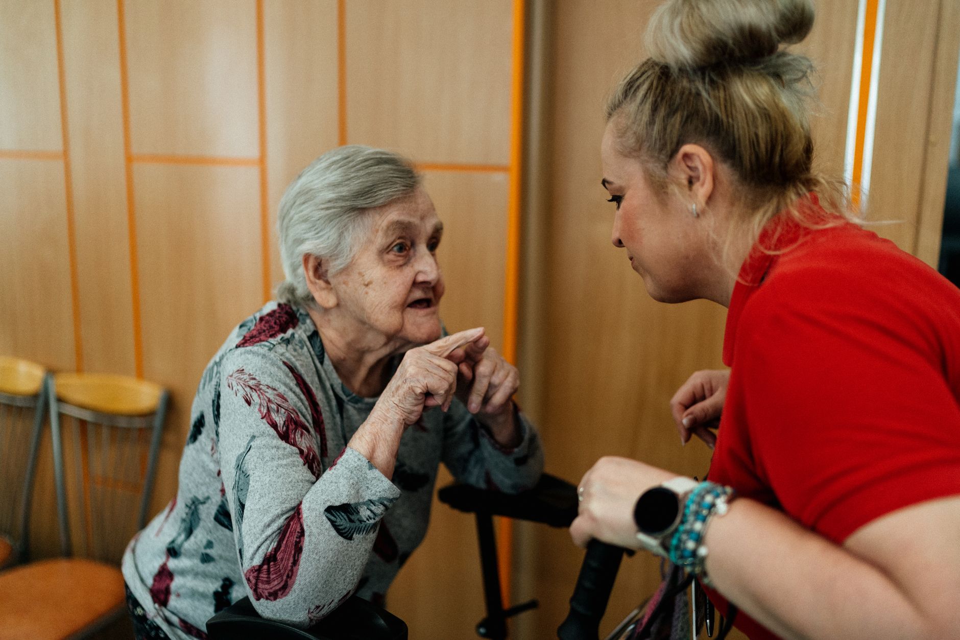 Elderly woman and caregiver in conversation inside a room in Karviná, Česko.
